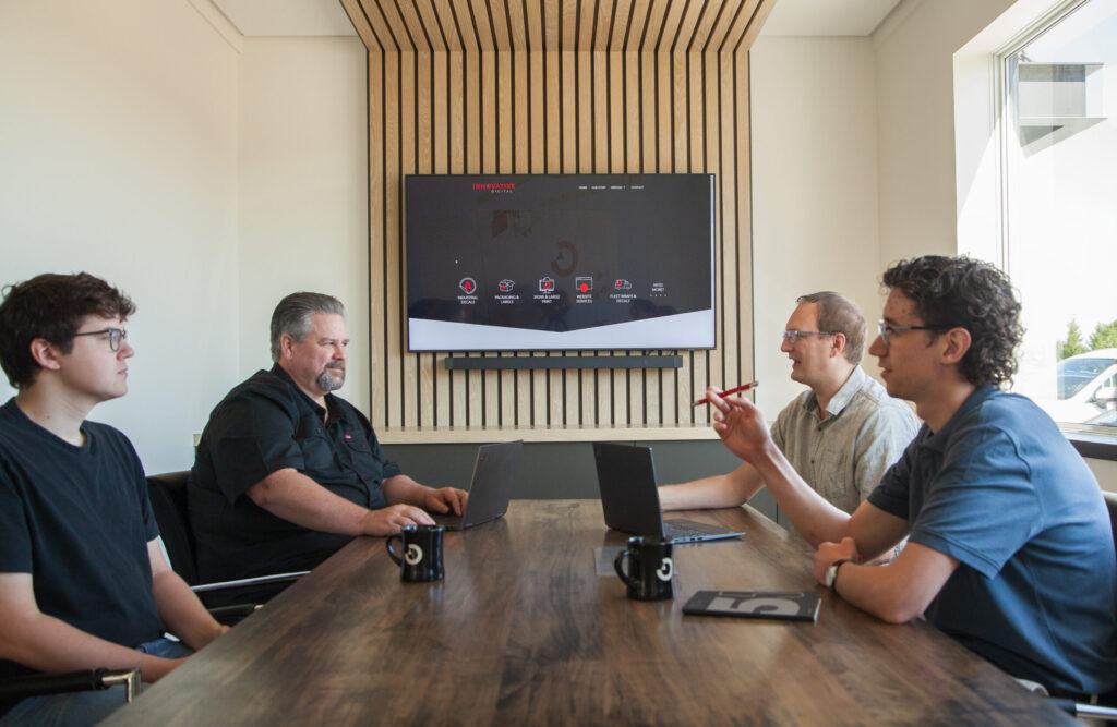 a group of men sitting at a table with laptops